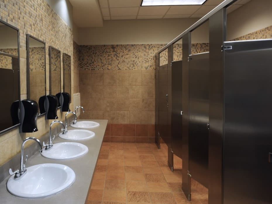 Modern commercial bathroom with multiple stalls and accessibility features